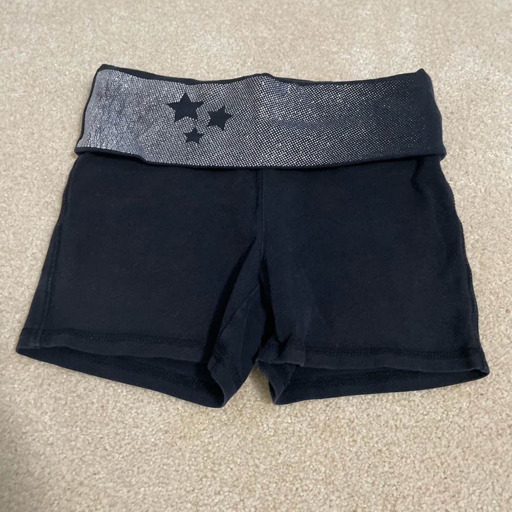 A pair of tight black girls shorts with a silver, glittery, starry waistband.